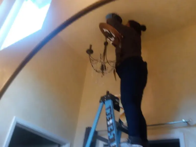 Electrician installing a chandelier in a Perham residence